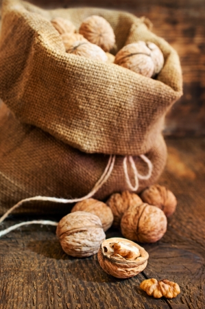 walnuts in a burlap bag on woodenの写真素材