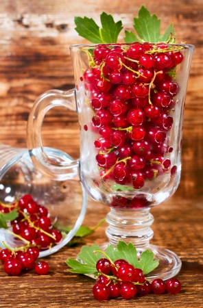 ripe red currants in a glass on a wooden backgroundの写真素材