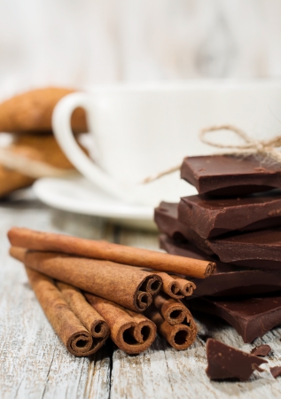 dark chocolate , cinnamon sticks and a cup of coffee on a wooden backgroundの写真素材