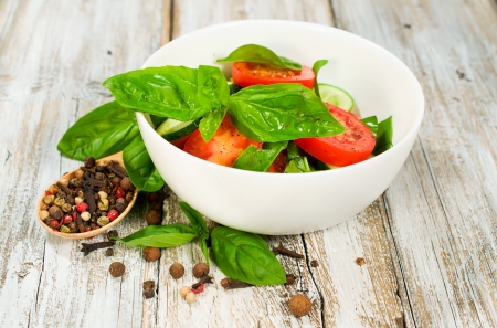 salad with tomatoes, cucumbers and basil on a wooden backgroundの写真素材