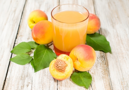 peach juice and fresh fruits with leaves on the wooden backgroundの写真素材