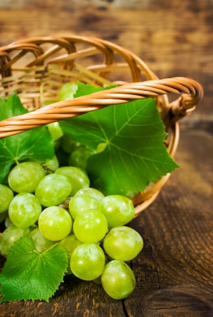 ripe green grapes in a wicker basket on wooden background close-upの写真素材