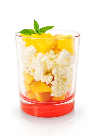 cottage cheese dessert with peaches in a glass isolated on whiteの写真素材