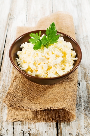 cottage cheese in a clay bowl on a wooden backgroundの写真素材