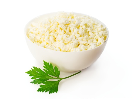 cottage cheese in a white bowl with a sprig of parsley isolated on whiteの写真素材