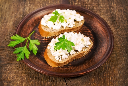 sandwiches with rye bread and cottage cheese on a clay plateの写真素材
