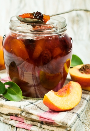 peach jam in a glass jar and fresh peachesの写真素材