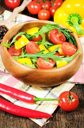 salad with cherry tomatoes , sweet peppers and rugula in a wooden bowlの写真素材
