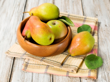 Ripe pears in a wooden bowl with leavesの写真素材