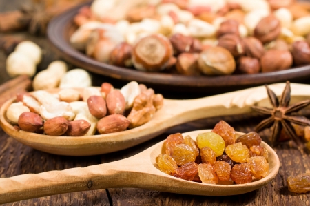nuts and raisins in wooden spoons close-upの写真素材