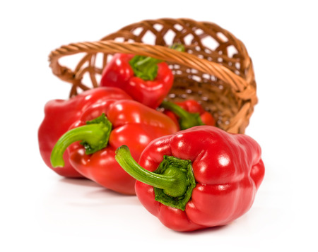 red peppers in a wicker basket isolated on whiteの写真素材