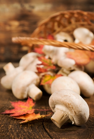 mushrooms with autumn leaves , and wicker basket on a wooden backgroundの写真素材