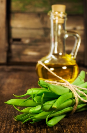 bunch of green beans and vegetable oil on a wooden backgroundの写真素材