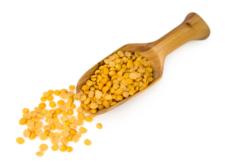 yellow lentils in a wooden scoop isolated on whiteの写真素材