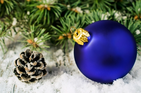 Blue Christmas ball and spruce branches in the snow close-upの写真素材