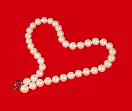 pearl necklace in the shape of heart on red backgroundの写真素材