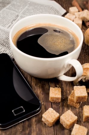 Breakfast concept: mobile phone, coffee and sugar cane on the wooden backgroundの写真素材