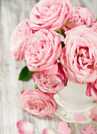 bouquet of pink roses in a vase on a painted wooden backgroundの写真素材