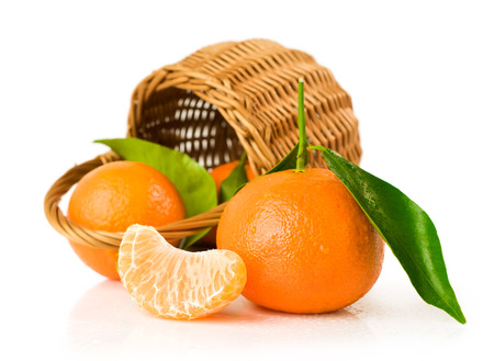 Ripe tangerines with basket isolated on whiteの写真素材
