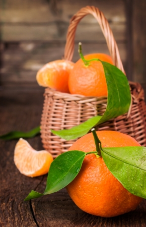Ripe tangerines with basket on a wooden tableの写真素材