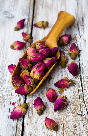 Roses flowers tea in a wooden scoop on a white backgroundの写真素材