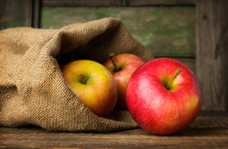 Red ripe apples in a bag on a wooden backgroundの写真素材