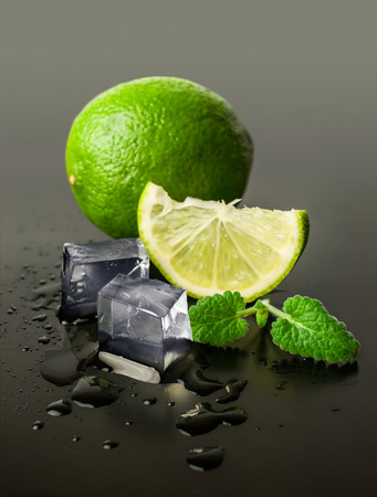 lime and mint with ice cubes on a black backgroundの写真素材