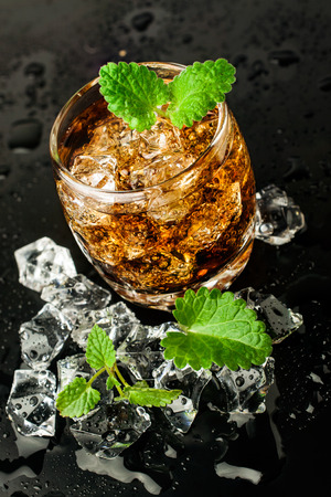 whiskey with ice and mint on black backgroundの写真素材
