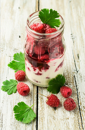 Raspberry dessert in a glass jar on a wooden tableの写真素材