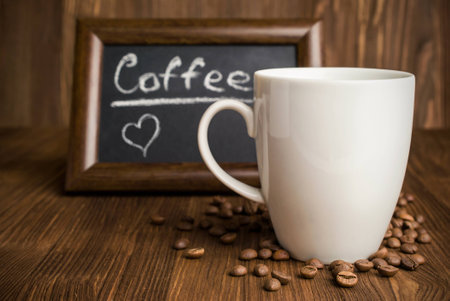 slate with coffee beans and a cup on a wooden backgroundの写真素材