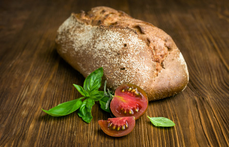 rye bread with tomato and basil on a wooden tableの写真素材
