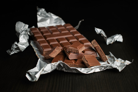 chocolate bar in silver foil on a dark backgroundの写真素材