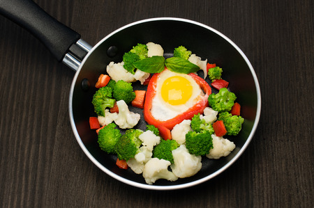 scrambled eggs with vegetables in a frying pan on blackの写真素材