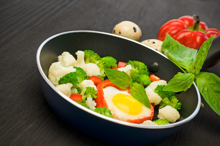 scrambled eggs with vegetables in a frying pan on black wooden