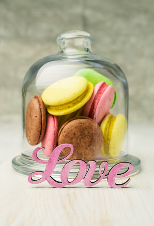 multicolored macaroons in a glass bell jar on tableの写真素材