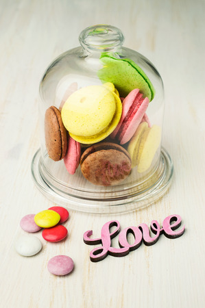 multicolored macaroons in a glass bell jar on tableの写真素材