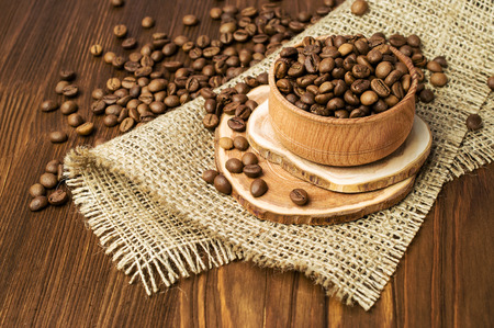 Roasted coffee beans in a wooden bowl on wooden backgroundの写真素材