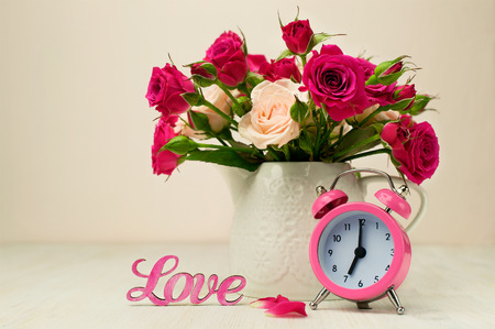 Valentines day still life. Bouquet of roses , pink alarm clock and the word "love"の写真素材
