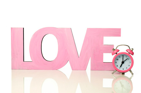 Pink word "love" with a small alarm clock isolated on whiteの写真素材