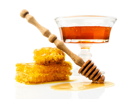 Honey with honeycomb and wooden dipper over whiteの写真素材