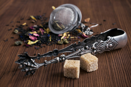 Herbal tea, tea strainer, sugar cubes and tongs on white backgroundの写真素材