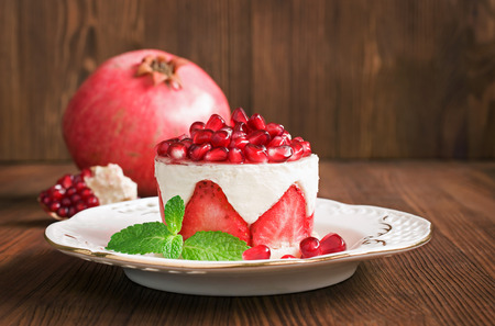 Cake with strawberry and pomegranate on a woodenの写真素材