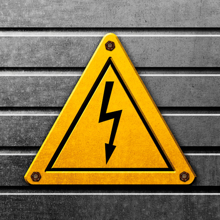 Yellow sign high voltage on metal backgroundの写真素材