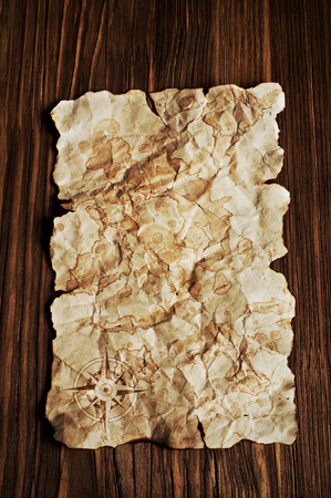 Ancient Parchment with wind rose and an old pirate map on wooden backgroundの写真素材