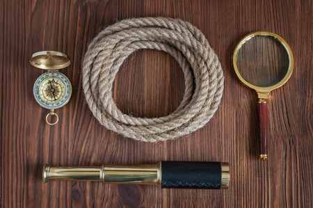Nautical collection: spyglass, compass, magnifying glass, rope lying on the wooden backgroundの写真素材
