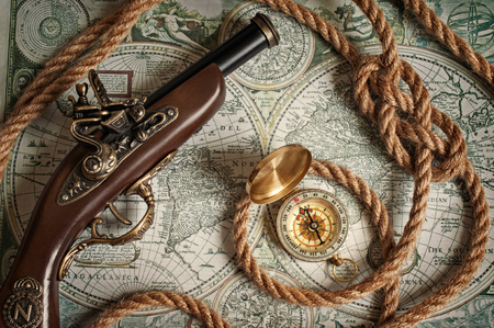 Ancient musket, compass and rope lying on the old map