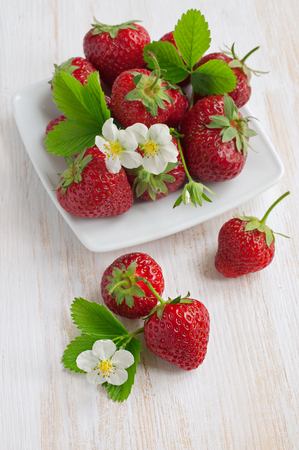 Ripe strawberry with leaves and blossom on the tableの写真素材