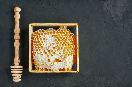 Honeycomb and wooden dipper on dark backgroundの写真素材
