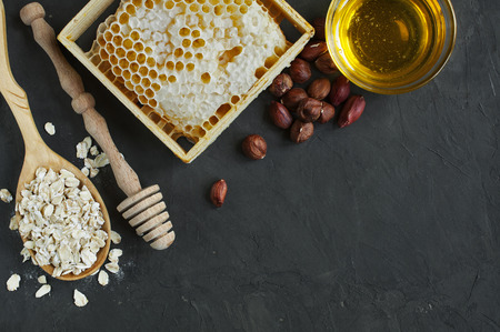 Honeycomb and nuts, and oatmeal and wooden dipper on dark backgroundの写真素材