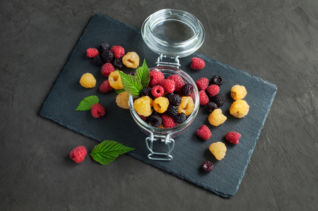 Raspberries mix: yellow, red and black raspberry on a black slate boardの写真素材